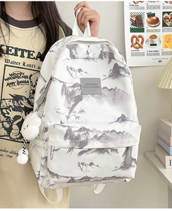 Detail eines weißen Rucksacks mit grauem Tusche-Landschaftsdruck und Wolkenanhänger