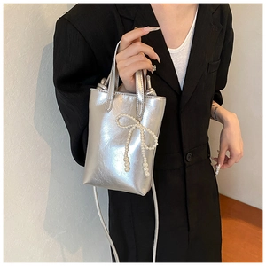 Vue détaillée d'un sac seau métallisé argenté avec un nœud en perles blanches