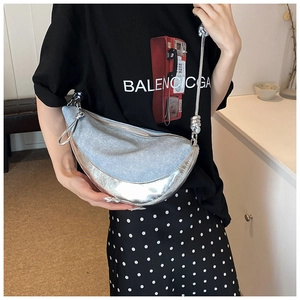 Detailed close-up of light blue denim hobo bag with silver mirror leather and knotted strap