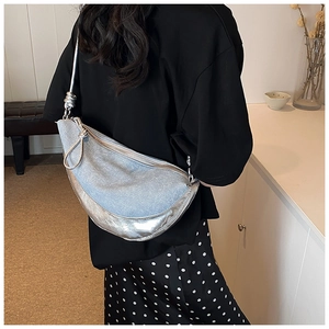Detail of blue denim and silver metallic patchwork on crescent-shaped shoulder bag