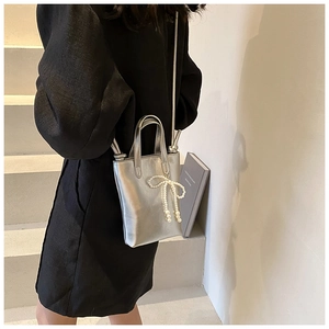 Détail du mini sac bandoulière argenté métallisé avec charm nœud en perles blanches