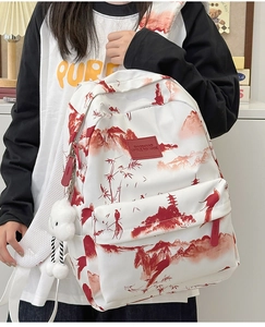 Detail eines weißen Rucksacks mit roten Tuschemalereien und flauschigem Anhänger