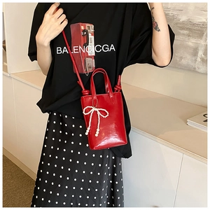 Détail du mini sac rouge avec nœud en perles et bandoulière à nœuds sur mannequin