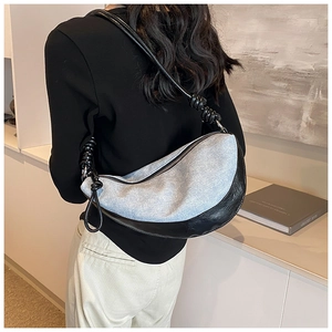 Detail of crescent shoulder bag featuring light blue denim and black leather patchwork
