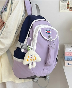 Close-up of lilac nylon backpack side view featuring white plush charm and navy accents