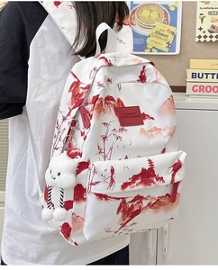 Detail eines weißen Canvas-Rucksacks mit roten Landschaftsdrucken und Wolkenanhänger