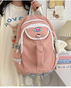 Close-up of pink nylon backpack with multiple compartments and cute plush toast keychain