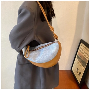 Close-up of blue denim and brown leather stitching on the crescent shoulder bag