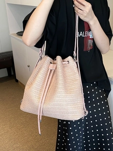 Pink straw bucket bag with drawstring closure and slim shoulder strap for summer travel