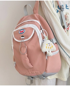 Detailed side view of pink nylon backpack with cute plush charm and zcmao embroidery