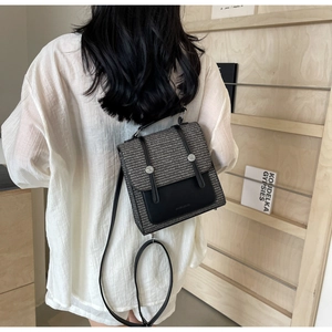 Detail of a mini woven backpack with black leather flap shown in an artistic lifestyle setting