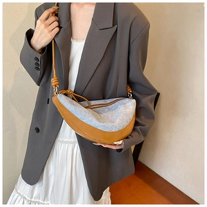 Detailed view of crescent denim shoulder bag with leather strap on a chic outfit