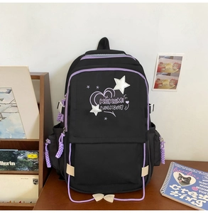Detail of black school backpack with purple zipper pulls and white star heart embroidery