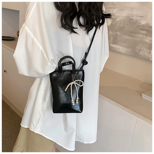 Détail du mini sac à main noir brillant avec pendentif perle et bandoulière