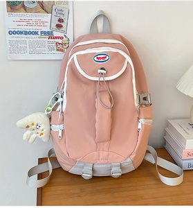 Pink nylon backpack detail showing durable fabric texture and white contrast zippers
