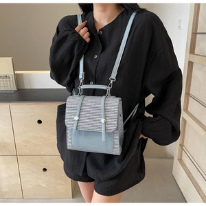 Detail of light blue mini backpack showing woven texture and leather flap on a model