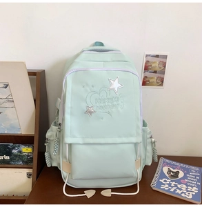 Detail of mint green school backpack featuring star embroidery and multiple zipper pockets