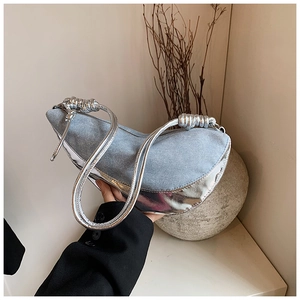 Detail of light blue denim crescent bag with silver metallic trim and twisted rope strap