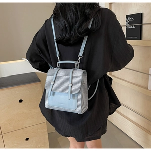 Detail of light blue woven fabric backpack with leather trim and adjustable straps