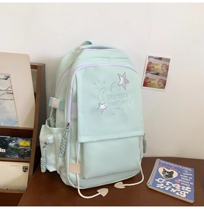 Detail of mint green school backpack with star embroidery on a wooden desk