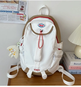 Close-up of nylon backpack with color-block design and pizza plush keychain on a desk