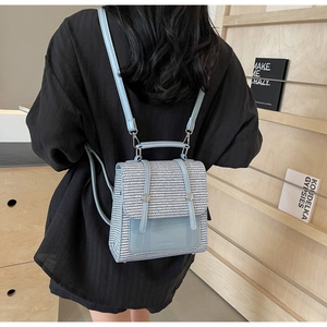 Detail of blue and white woven mini backpack with silver metal handle on a model