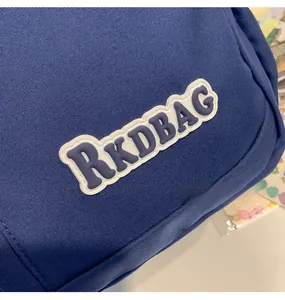 Detailed close-up of RKDBAG rubber label on dark blue canvas backpack material