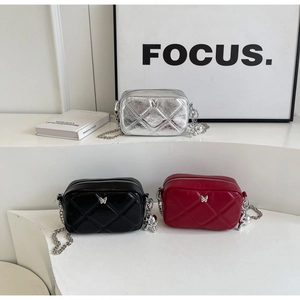 Detail of three quilted mini camera bags in silver, black and red with metal butterfly