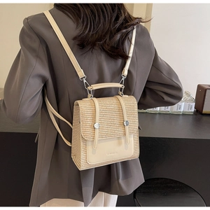 Detail of cream woven backpack with silver buckles and faux leather accents on model