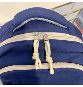 Detail of smooth two-way zipper and woven rope pulls on a navy canvas backpack