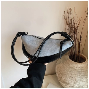 Detail of hobo bag featuring grey denim fabric and black leather trim with knotted strap
