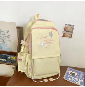 Detail of yellow nylon backpack featuring pink zipper trim and star embroidery on wood table