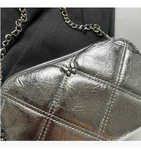 Detail of silver metallic quilted handbag with butterfly buckle and shiny chain strap