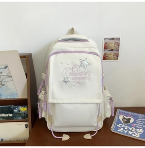 Detailed close-up of cream school backpack with purple trim and embroidered star patterns