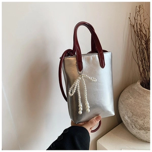 Mini sac argenté avec poignée rouge et détail de breloque nœud en perles