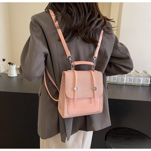 Rear view of a pink woven texture backpack worn on a model with brown suit