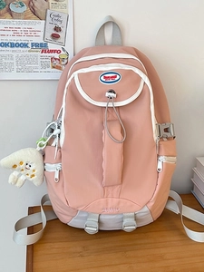 Pink nylon backpack for women with water-resistant fabric and plush charm on wood table
