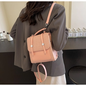 Detail view of pink woven texture backpack with silver buckles worn by a model