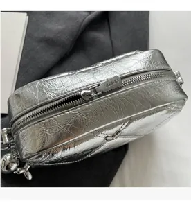 Detail of silver metallic rhombic bag showing smooth zipper and shiny textured finish