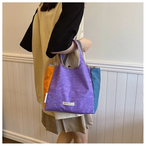 Detail of color-block nylon tote bag with purple orange and blue patchwork texture