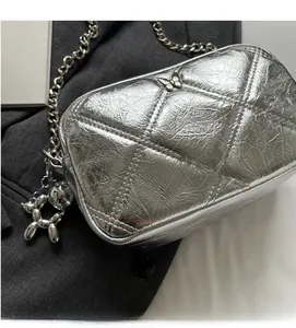 Detail of silver quilted chain bag featuring metallic texture and balloon dog charm