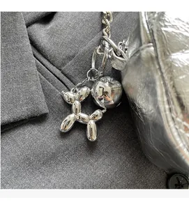 Close-up of a silver balloon dog charm with polished mirror finish on a chic handbag