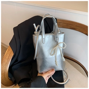 Détail d'un mini sac argenté métallisé avec nœud en perles et design fourre-tout vertical