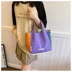 Detail view of colorful patchwork canvas tote bag featuring vibrant purple and orange panels