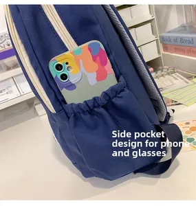 Detail of canvas backpack side pocket with elastic band holding a mobile phone