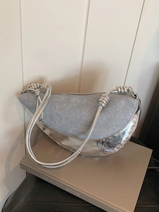 Blue denim and silver mirror leather half-moon shoulder bag on books