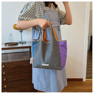 Detail of color-block tote bag with pleated texture and stylish side logo label