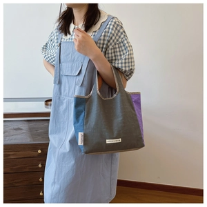 Detail of color-block canvas tote bag featuring grey, blue, and purple fabric panels
