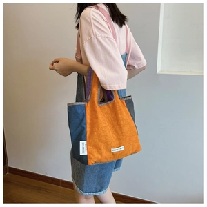 Detail of colorful patchwork pleated nylon tote bag with brand label showing large capacity