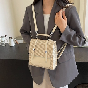 Minimalist beige straw backpack with cream leather straps worn over a grey blazer